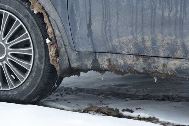 Snow and dirt buildup on the tires and undercarriage of a vehicle.