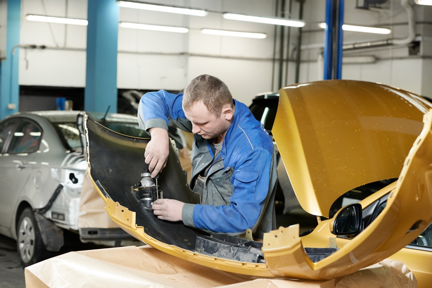 A repair technician performing collision repair on parts of a vehicle.